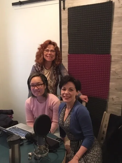 Women smiling around a microphone setup