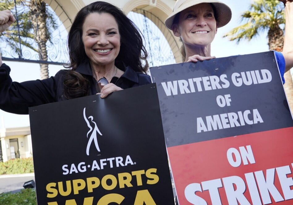 two women hold picket signs that say SAG-AFTRA supports WGA and Writers Guild of America on Strike