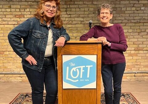 two white women pose at a podium